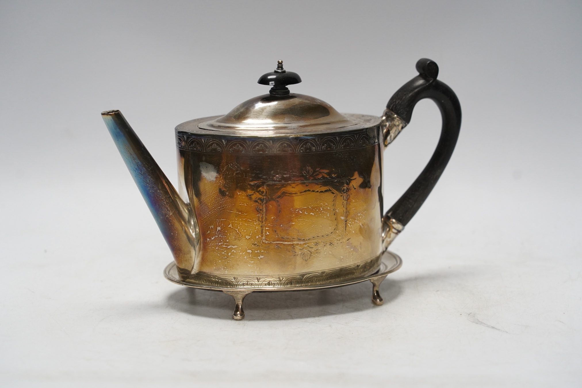 A George III engraved silver oval teapot, Cornelius Bland, London, 1791(poor condition), together with an associated oval stand (fair condition), Soloman Hougham, London, 1797, 16.2cm, gross 16oz.